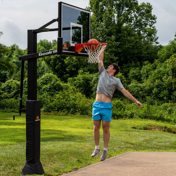 Load image into Gallery viewer, Person playing basketball with a Goalrilla basketball hoop in a park setting.
